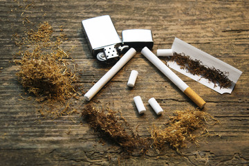 Accessories for rolling and smoking cigarettes on a rustic woode - obrazy, fototapety, plakaty