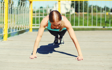 Sport, fitness concept - woman doing push-ups exercise in city