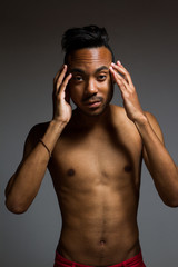 Fototapeta premium Latin man posing indoor over a grey wall.