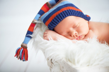 Cute newborn baby in blue knit cap sleeping in basket