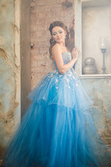 Fototapeta na wymiar Beautiful young woman in gorgeous blue long dress like Cinderella with perfect make-up and hair style