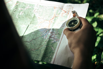 traveler exploring map with compass in sunny forest in the mount