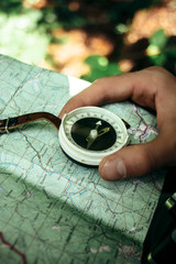 traveler exploring map with compass in sunny forest in the mount