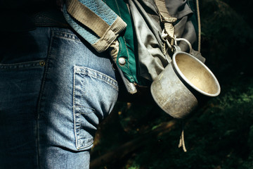 stylish metal cup on traveler backpack in sunny forest in the mo