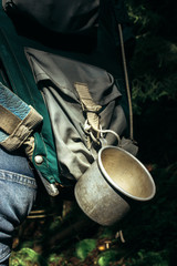 stylish metal cup on traveler backpack in sunny forest in the mo