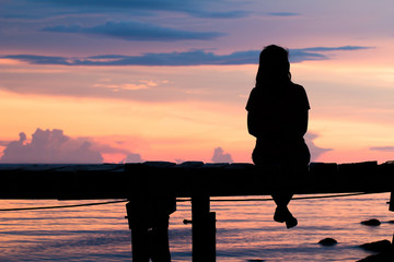 Lonely woman sitting on a wooden bridge sunset.are Lonely. style abstract shadows.silhouette