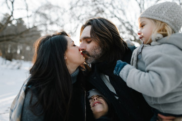 Fototapeta premium Happy young hipster family having fun, bowl, rising up, piggyback ride their children and relax in park on winter sunset