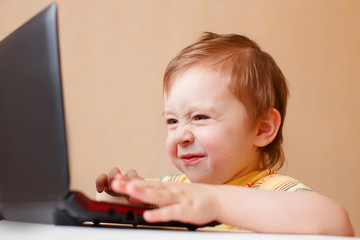 little smart boy surfing the Internet on laptop. child saw something unpleasant on the computer screen, and wrinkled his nose. the concept of parental control Internet