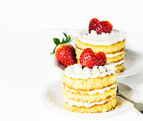 Two sponge cakes with cream and strawberries for Valentines day on  a white table. Selective focus.