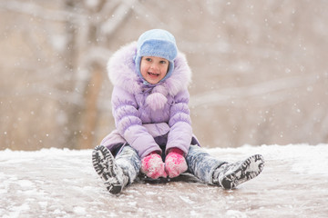 Fototapeta na wymiar Joyful child slides down the icy hill