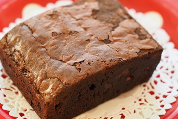 Chocolate brownie on white doily paper closeup