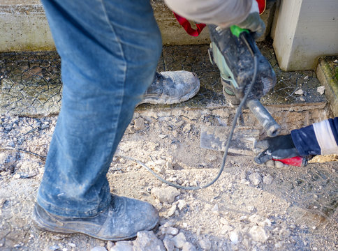 Construction site - workers using Jackhammer and trowel performing track on the floor sidewalk.Selective focus and motion blur