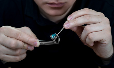 Jeweler holding a ring with a stone. 