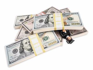 Photograph of figurine of unhappy female graduate in cap and gown buried under stacks of U.S. paper currency, suggesting the idea of the high price of education and crushing student loans.