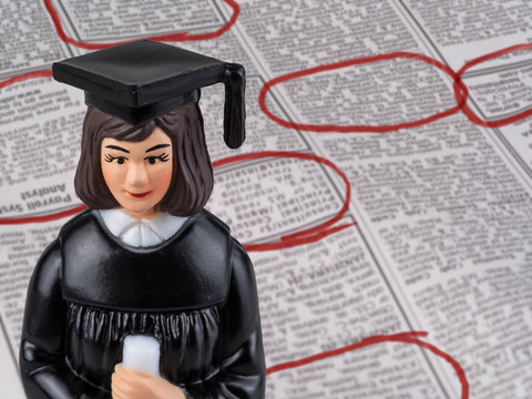 Photograph Of A Female Graduate Figurine In Cap And Gown And Holding A Diploma Set Before The Employment Section Of The Newspaper.