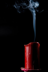 extinguished candle of red color on a dark background