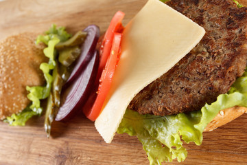 Traditional American cheeseburger. Meat, bun and vegetables close up
