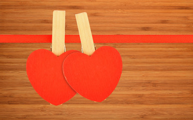 Two red hearts at ribbon over bamboo wood