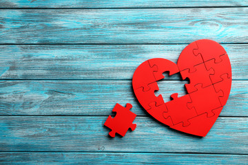Red puzzle heart on blue wooden background - Powered by Adobe