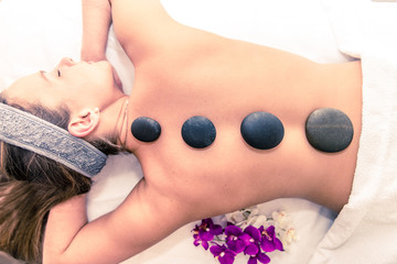 Obraz na płótnie Canvas Woman having massage with hot stones
