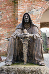 Statue of an executioner sitting down with his weapon in a medieval setting