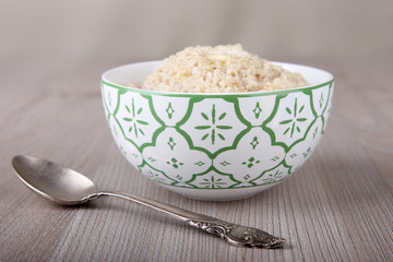 Oatmeal porridge in bowl with spoon on wooden table