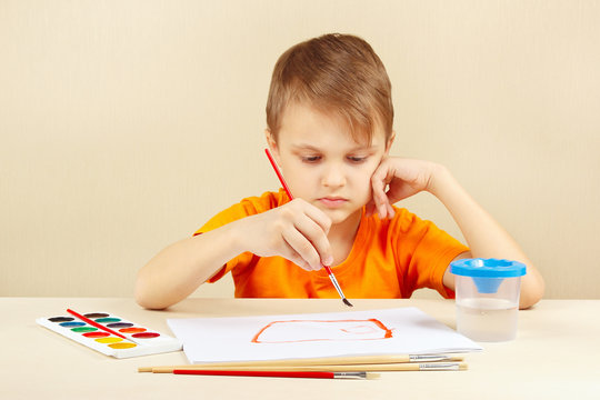Little boy in an orange shirt painting colors