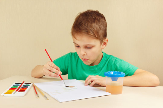 Little artist in a green shirt painting with watercolors