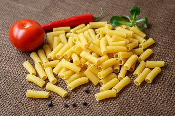 Rigatoni raw pasta on background of jute