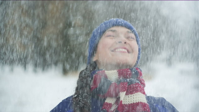 Young cheerful woman throwing up snow