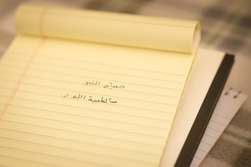 Arabic; Learning New Language Writing Greetings on the Notebook