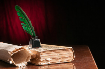Green quill pen and a rolled papyrus sheet