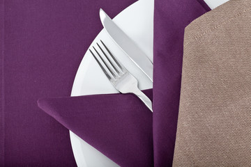 Top view of the beautifully decorated table with white plate, linen napkins and cutlery on...