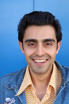portrait of beaming young man with an absolute perfect white smile on blue background 