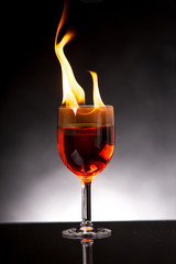 wine glass with burning alcohol on black background
