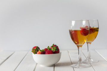 Wine in Glasses and a Bowl of Strawberries on a White Wooden Table with Copy Space