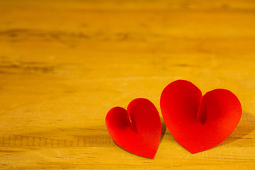 Two red paper love shape placing beautifully on wooden table