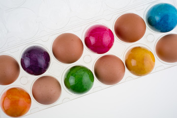 Easter and brown eggs in a clear plastic carton
