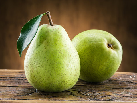Two pears with leaf on wooden background.