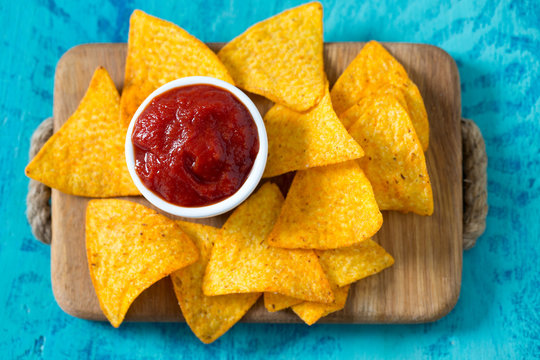 tortilla chips and tomato dip on wooden surface