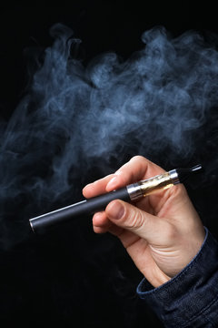 Hand holding electronic cigarette  on a black background