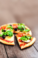 Pizza with fresh vegetables over rustic wooden table top view cl