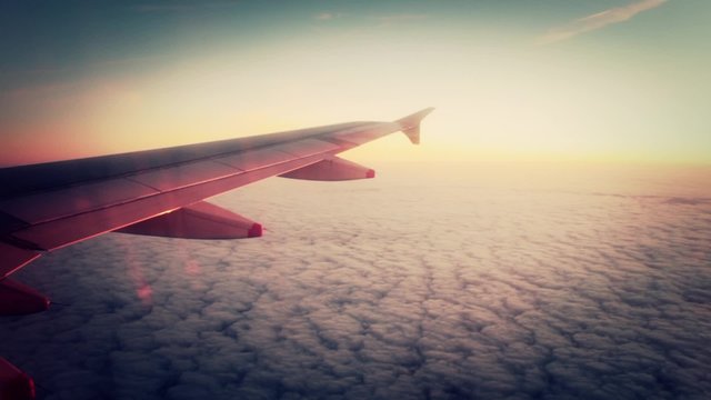 Flying over dramatic sunset cloudy sky - 1080p. Airplane wing flying over a sunset cloudy sky. Cinematic scene. Full HD