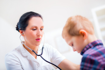 Happy little boy at the doctor for a checkup - being examined with a stethoscope
