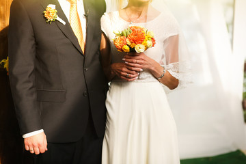 gorgeous stylish happy bride and groom standing near orange wood