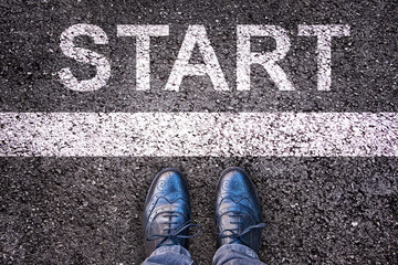 Word Start written on an asphalt road with legs and shoes