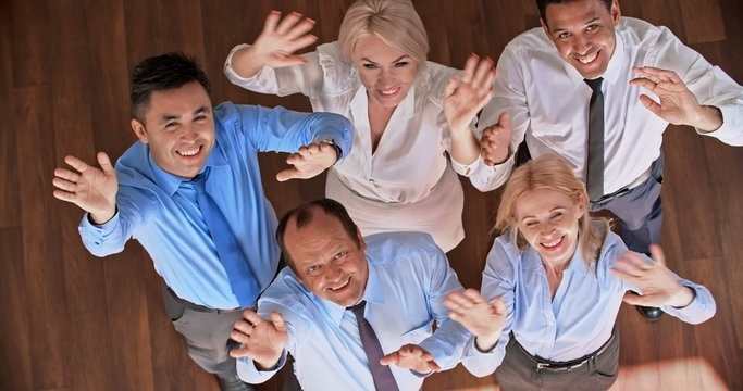 Multi-ethnic group of colleagues smiling and waving at the camera