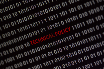 'Technical policy' text in the middle of the computer screen surrounded by numbers zero and one. Image is taken in a small angle.