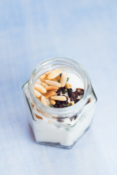 Greek yogurt with roasted pine nuts,  marinated dried tomatoes and thyme in jar. Healthy snack. Selective focus.