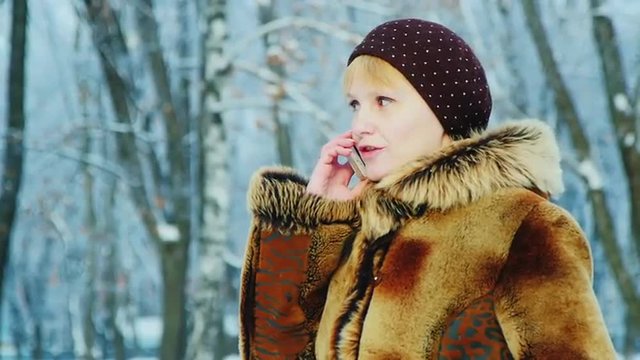 A woman in a fur coat talking on a mobile phone